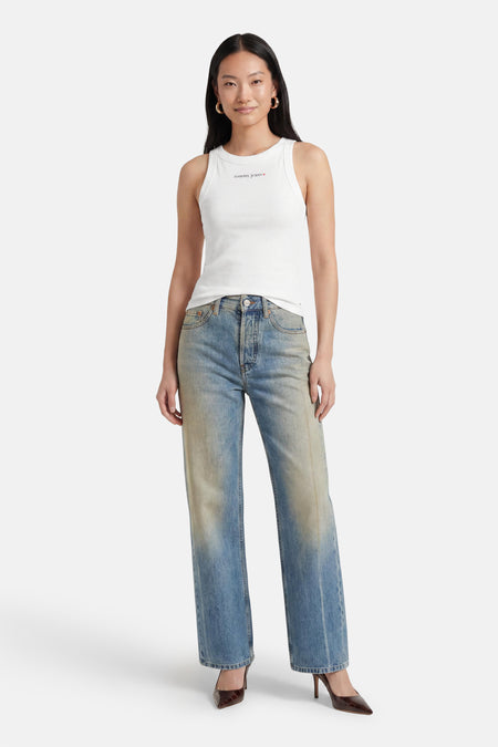 Witte tanktop van TOMMY JEANS met klein logo op borst, gedragen met blauwe jeans en bruine hakken, front view