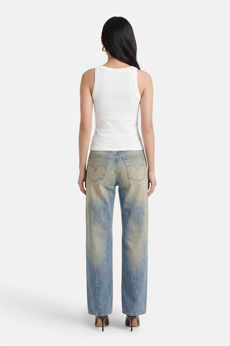 Witte ribbel tanktop van TOMMY JEANS, strak model, achterzijde, met lichtblauwe jeans en hoge hakken