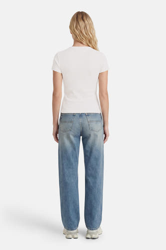 Witte korte mouwen t-shirt van TOMMY JEANS, strak model, achterkant weergegeven, gedragen met lichtblauwe jeans en witte sneakers