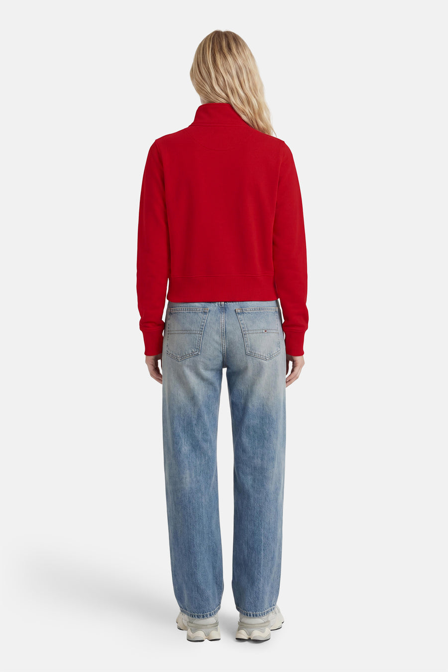 Rode ronde hals sweater van TOMMY JEANS, achterkant, met ribboorden en strakke pasvorm, gedragen met lichtblauwe jeans en witte sneakers.