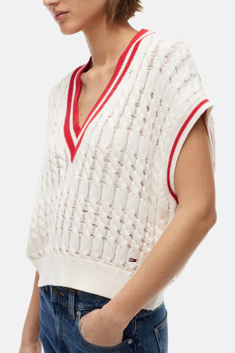 Ecru mouwloze gilet van TOMMY JEANS met opengewerkt kabelpatroon, gestreepte V-hals en armsgaten, en een klein logovlaggetje.