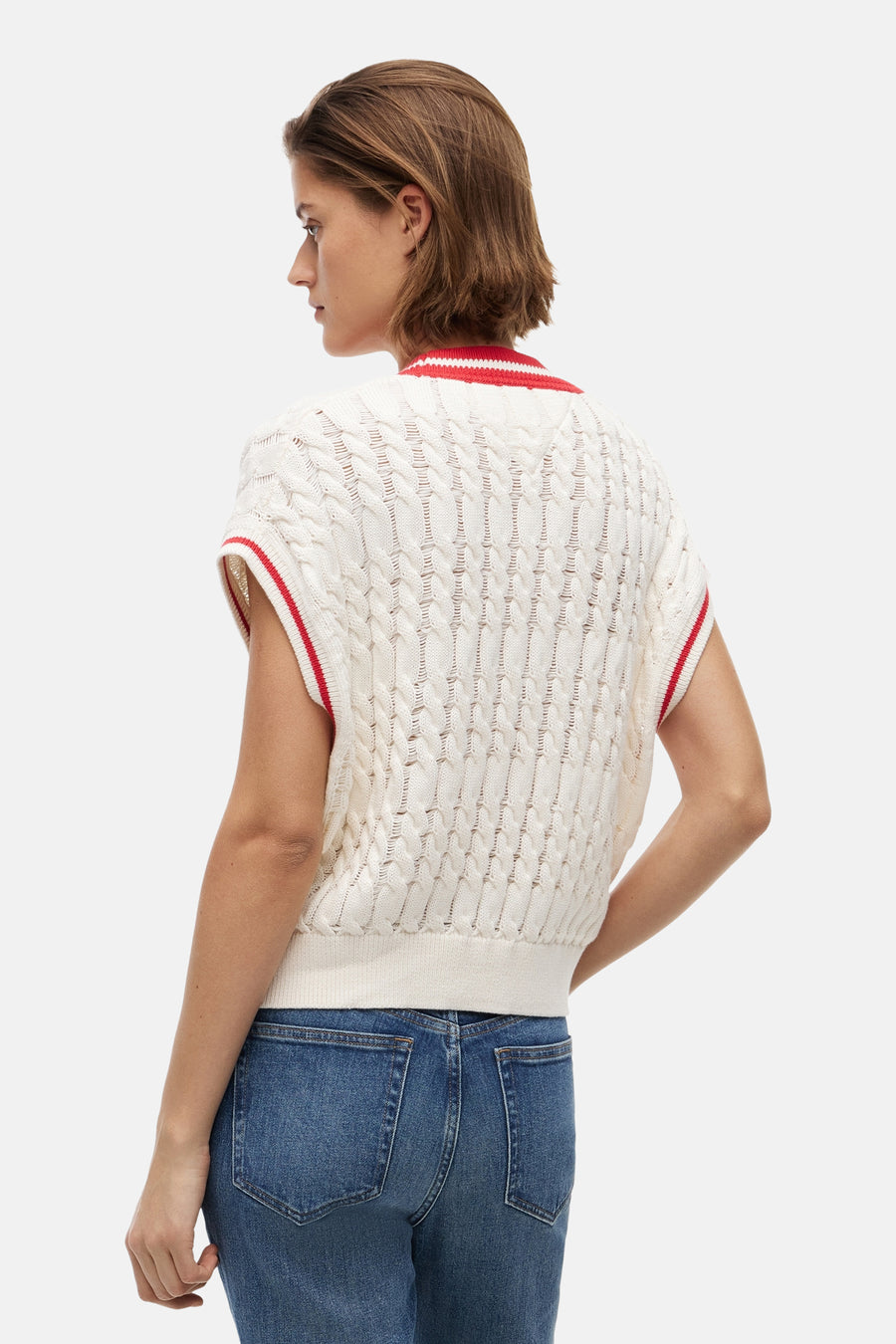 Débardeur écru de TOMMY JEANS avec tricot torsadé, bordures à rayures rouges et blanches et ourlet côtelé, vu de dos sur un jean bleu.