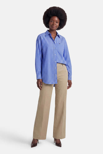 Blauw gestreept lange mouwen overhemd van TOMMY JEANS, voorzien van knoopsluiting en borstzakje, gedragen met beige broek en bruine hakken, front view.