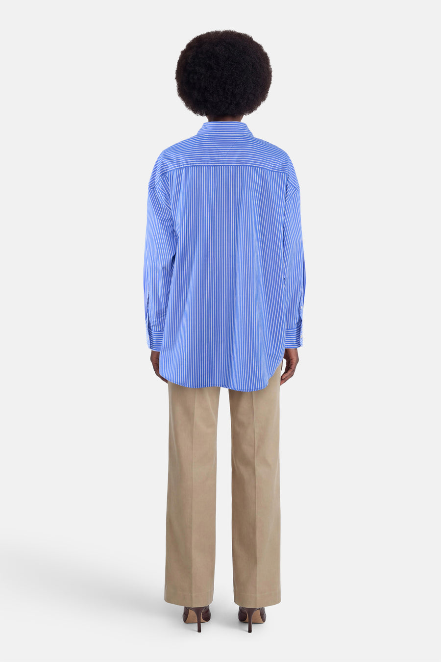 Blauw gestreept overhemd met lange mouwen van TOMMY JEANS, achterkant, losse pasvorm, witte strepen, model draagt beige broek en hoge hakken
