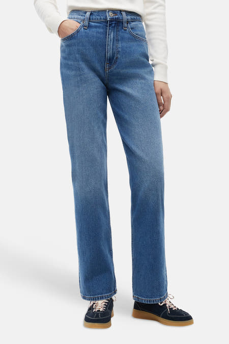 Midblauwe rechte jeans van TOMMY JEANS, front view, met lichte wassing en klassieke zakken, gedragen met witte trui en donkere sneakers.