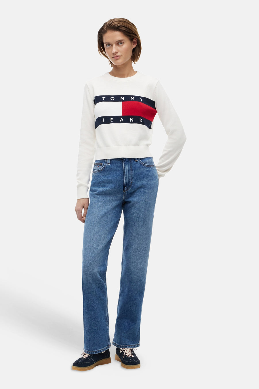 Mid blue straight jeans van TOMMY JEANS, gedragen met witte sweater met logo, donkere sneakers, front view