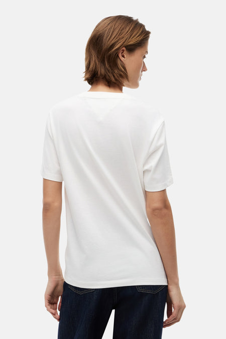 T-shirt écru de TOMMY JEANS, vue arrière avec coutures subtiles en forme de V dans le dos, porté par une femme sur un jean foncé.