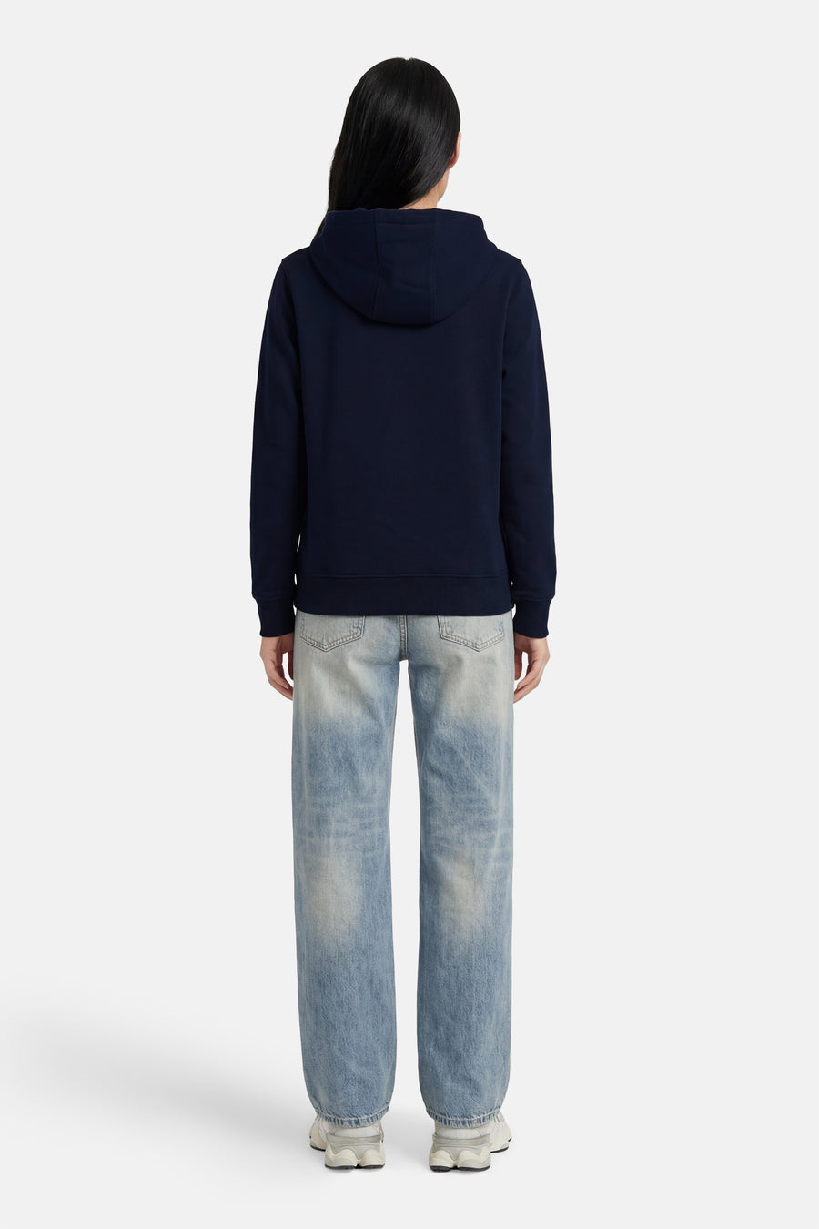 Donkerblauwe sweater met kap van TOMMY JEANS, achterzijde, gladde stof, model draagt lichte jeans en witte sneakers
