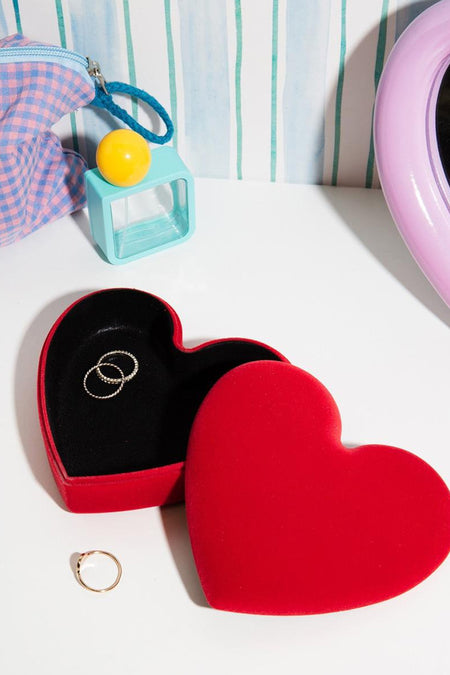 Rode hartvormige sieradenbox van fluweel van THE WOW EFFECT COMPANY, open met zwarte binnenkant en ringen, lifestyle-opstelling