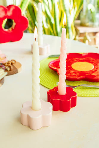 Article de cadeau rouge de DOIY, avec des supports de bougies en forme de fleur et des bougies tournées sur une table décorée.