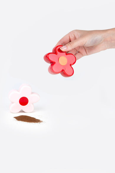 Rode bloemvormige zoutstrooier van DOIY, met bruin strooisel en een roze peperstrooier.
