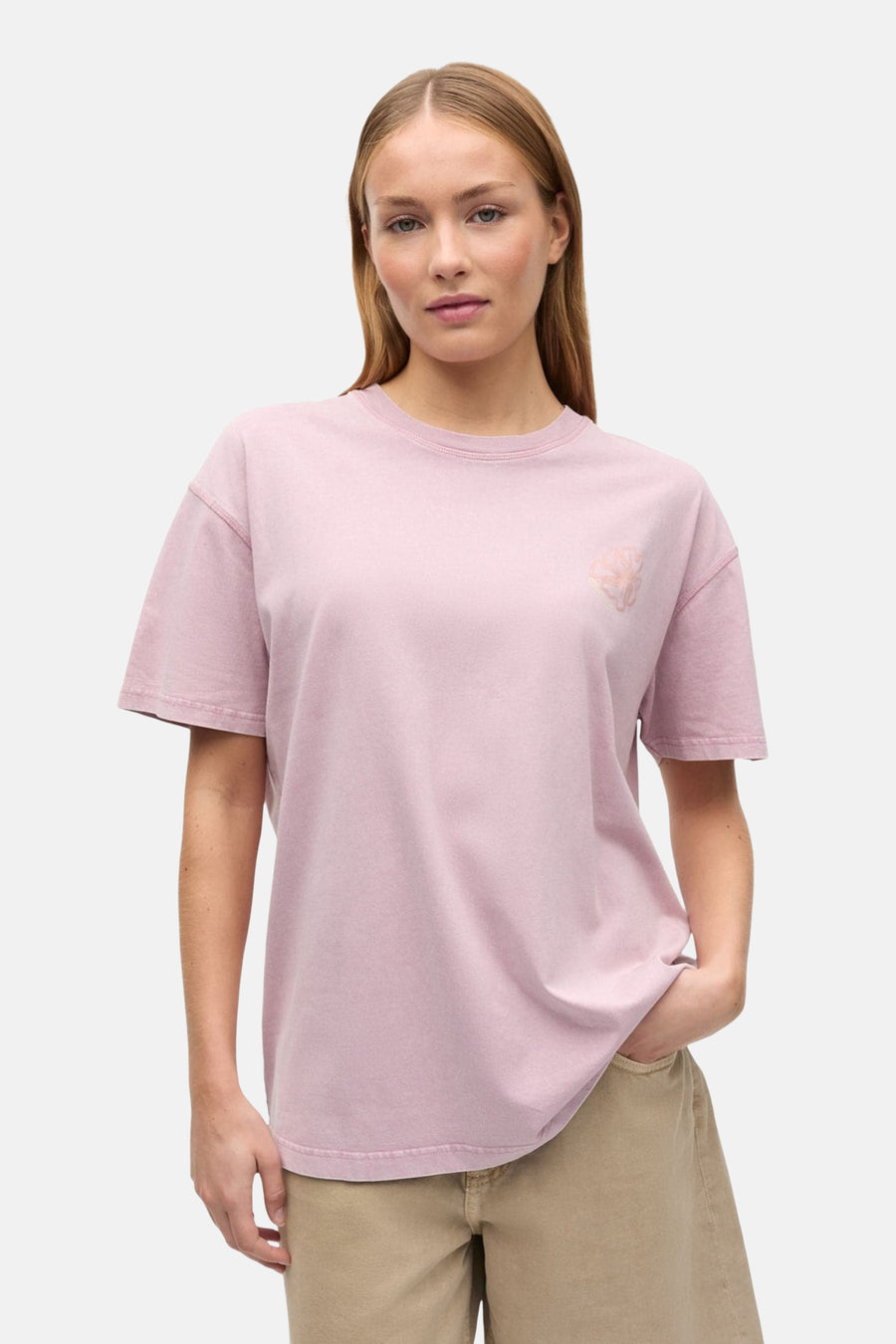 Roze T-shirt van ENVII met korte mouwen en een subtiele, lichtroze print op de borst, gedragen met een beige broek.