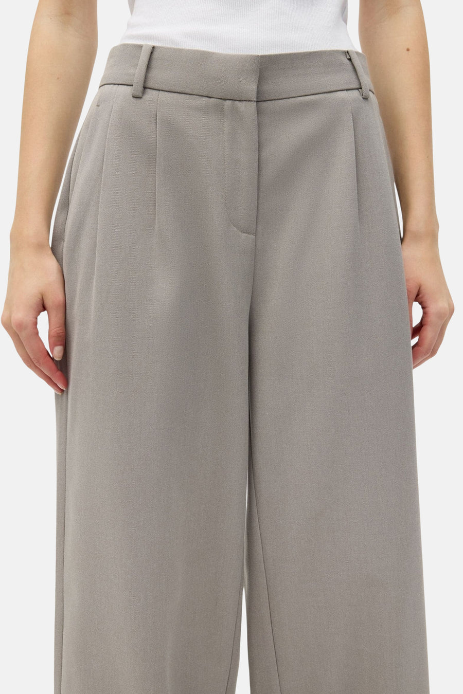 Beige broek van ENVII, met plooien en wijde pijpen, gezien van voren.
