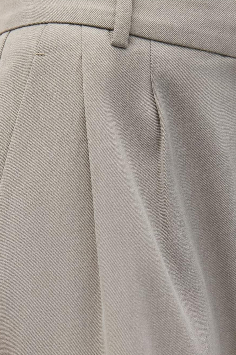 Pantalon beige d'ENVII, avec des plis et un détail de passant de ceinture.