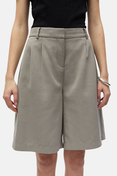 Grijze short van ENVII, met plooien aan de voorzijde en een zilveren armband.
