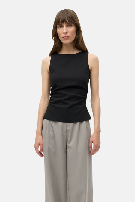 Zwarte top van ENVII, mouwloos met een aansluitende pasvorm en gedragen met grijze, wijde broeken.
