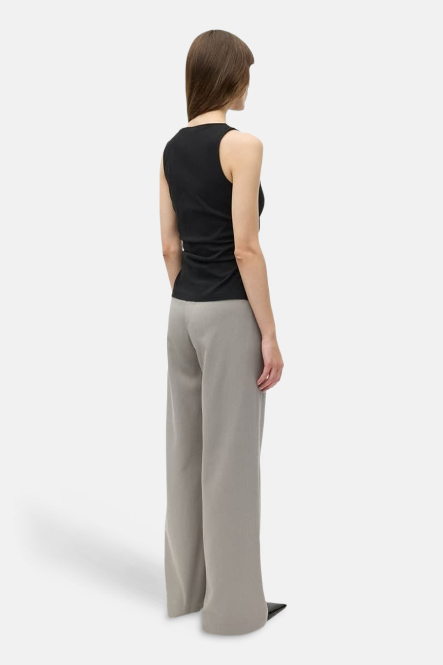 Zwarte top van ENVII, gezien van achteren, gecombineerd met een wijde, grijze broek en zwarte schoenen.