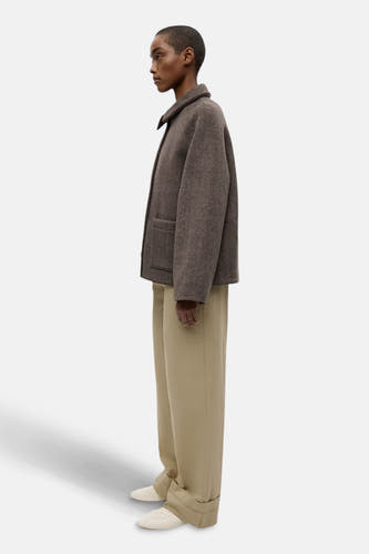 Bruine korte jas van ENVII, met lange beige broek en witte schoenen, in zijaanzicht.
