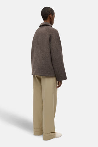 Bruine korte jas van ENVII, met lange mouwen en een kraag, gedragen met beige broeken.

