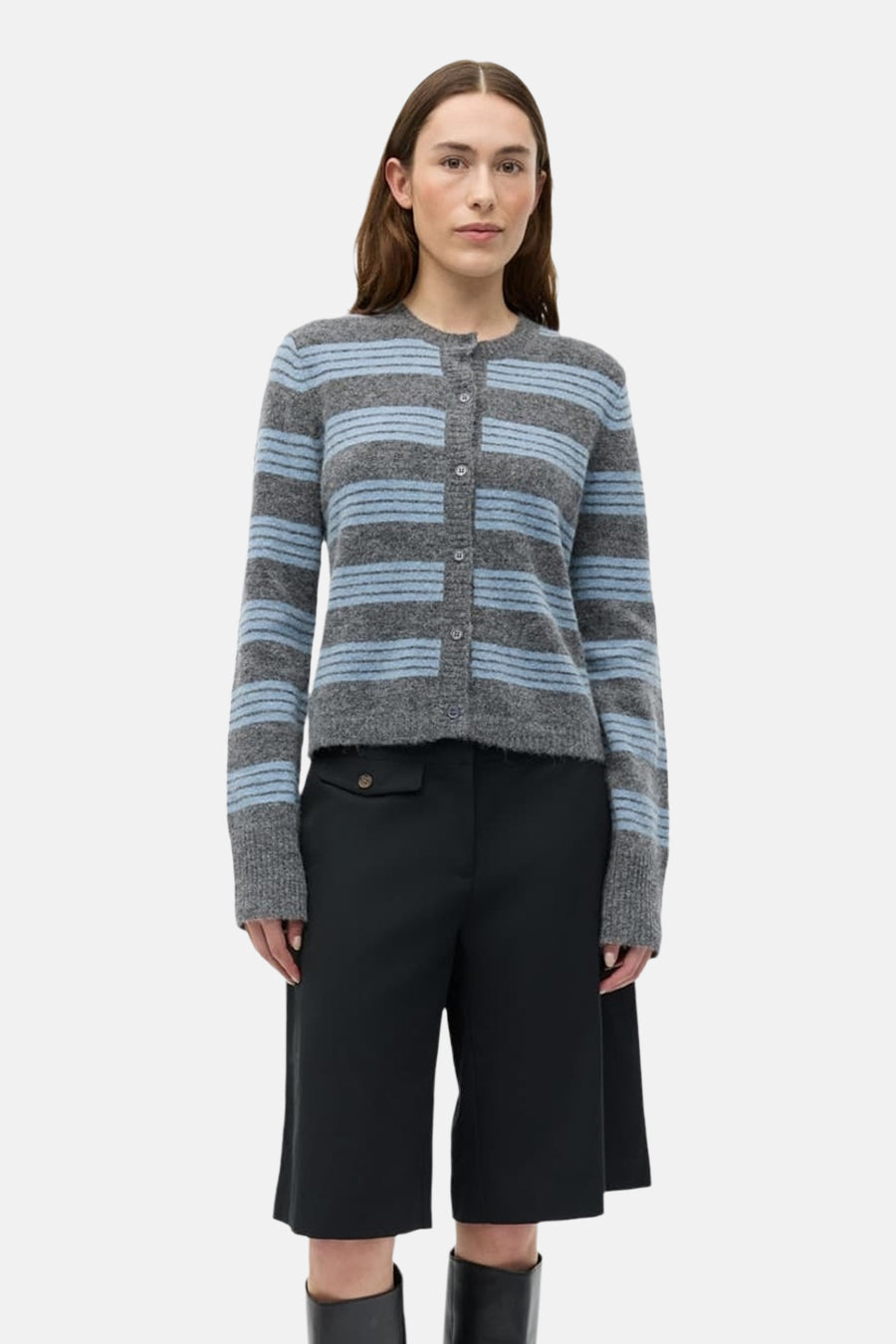 Gilet gris d'ENVII avec des rayures bleues, porté avec des culottes noires et des bottes noires.
