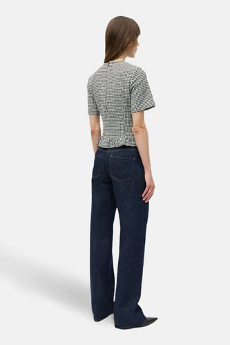 Wit geruite blouse met korte mouwen van ENVII, met ruches aan de onderkant, gecombineerd met een donkerblauwe spijkerbroek.
