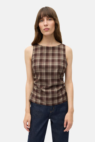 Mouwloze blouse in bruin ruitpatroon van ENVII, gecombineerd met een donkere jeans.
