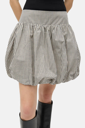 Beige korte rok van ENVII, met een ruitpatroon en gedragen met zwarte laarzen.
