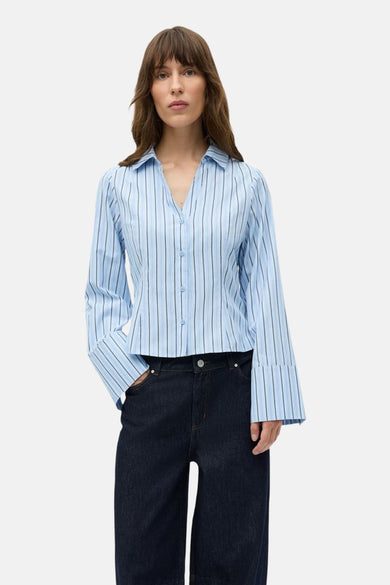 Chemise bleue à rayures avec longues manches d'ENVII, avec col boutonné et manches larges, associée à des jeans foncés.
