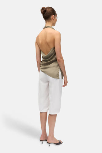 Groene mouwloze blouse van ENVII, achterzijde met open rug en drapering, gedragen met witte korte broek en zwarte sandalen