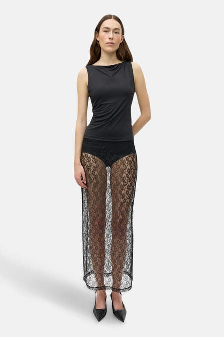 Robe longue noire d'ENVII, avec un motif floral en dentelle et portée avec une chemise noire et des escarpins.