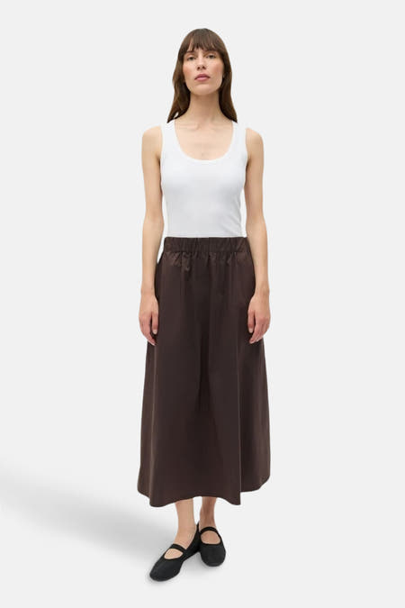 Bruine rok van ENVII, gecombineerd met een witte tanktop en zwarte ballerina's.
