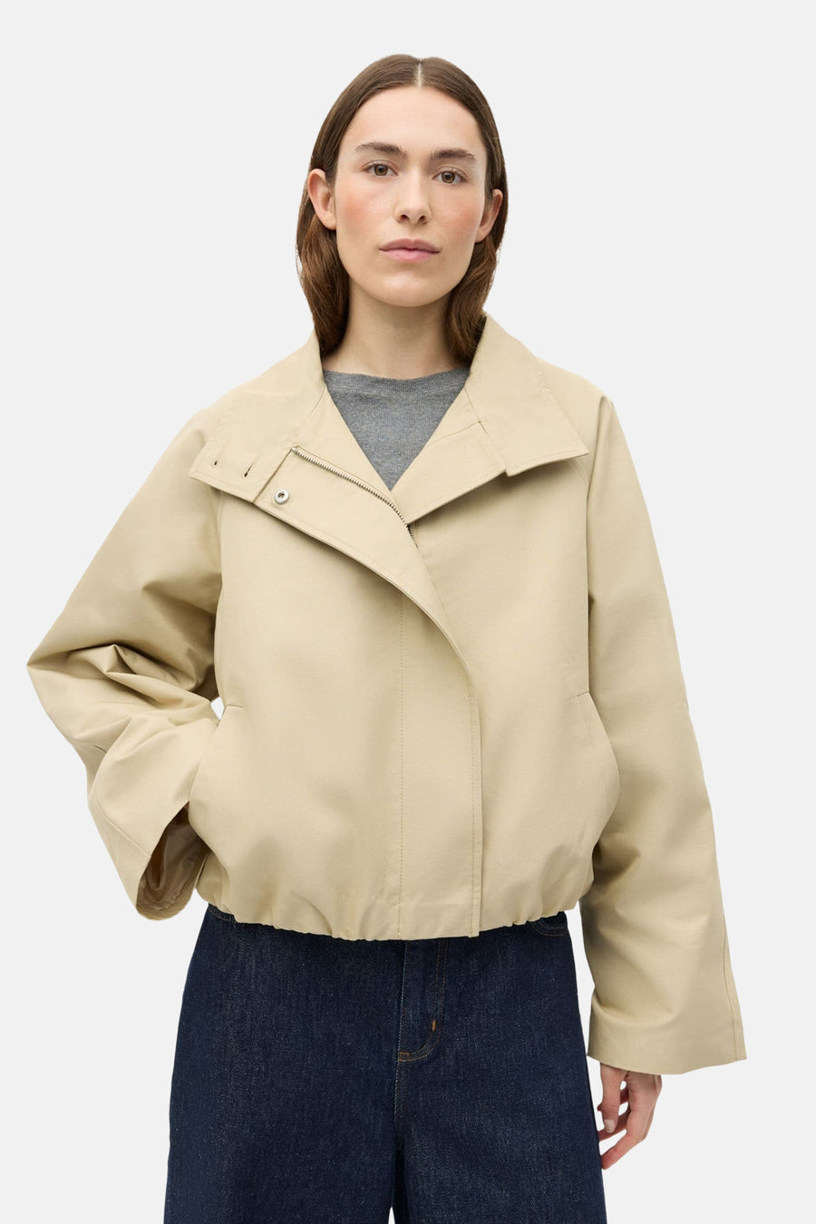 Manteau court beige d'ENVII, à manches longues, combiné avec un jean bleu foncé ample et des bottes noires.