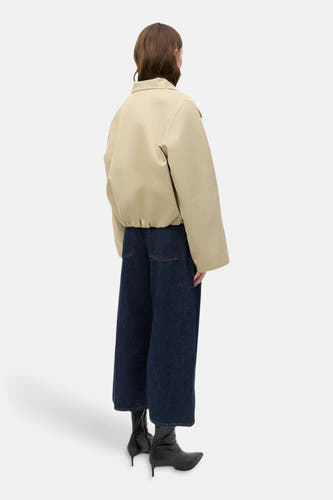 Beige korte jas van ENVII, met lange mouwen, gecombineerd met wijde donkerblauwe jeans en zwarte laarzen.