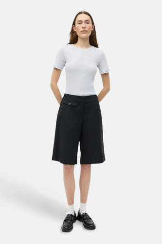 Short ample noir d'ENVII avec poche à rabat, porté par un mannequin dans une chemise gris clair et des mocassins noirs.