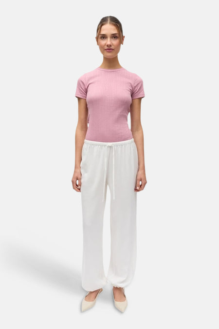 Pantalon blanc d'ENVII avec cordon de serrage et coupe décontractée, porté avec un haut rose et des chaussures claires.