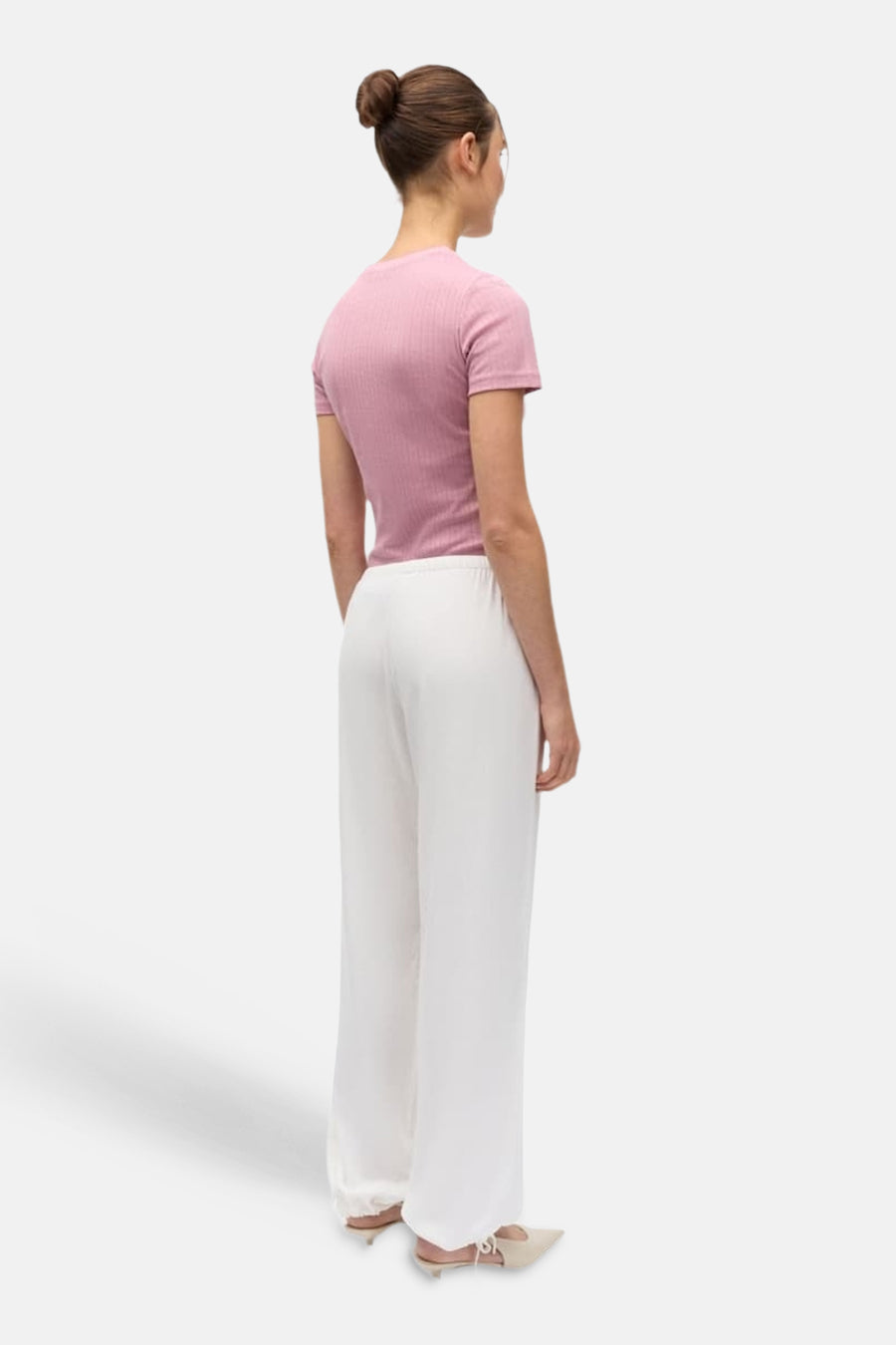 Witte broek van ENVII met wijde pijpen, gedragen door een model in roze geribbelde top, achterkant.