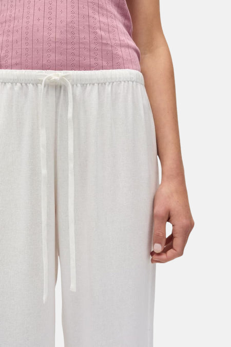 Pantalon blanc d'ENVII avec cordon de serrage à la taille, texture lin léger et une partie d'un haut rose.
