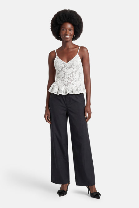 Witte mouwloze blouse van ENVII van kant met V-hals en peplumzoom, gecombineerd met een zwarte broek en hakken.