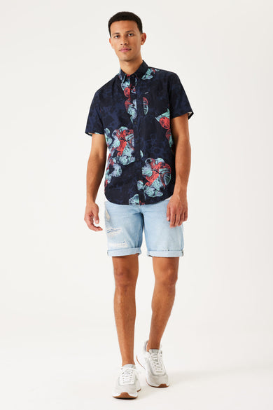 Blauw overhemd met korte mouwen van GARCIA, met een opvallend bloemmotief in rood en blauw, gecombineerd met denim shorts en witte sneakers.
