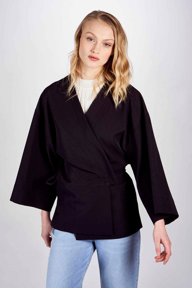 Blazer noir DEUX. par Eline De Munck, avec des manches larges et une ceinture, vu de derrière.