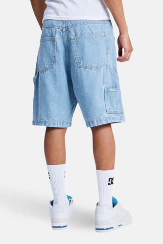 Lichtblauwe denim jeansshort van DC SHOES, met zakken aan de achterkant, gedragen met witte sokken en witte sneakers.