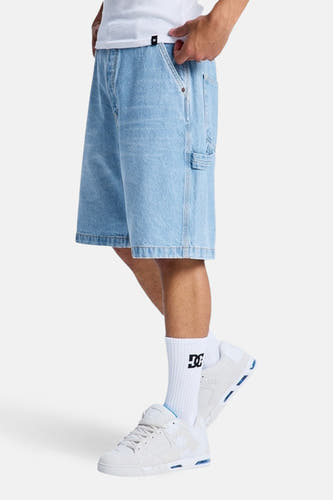 Short en jean en denim bleu clair, de DC SHOES, avec poche à outils et porté avec des chaussettes blanches et des baskets basses.