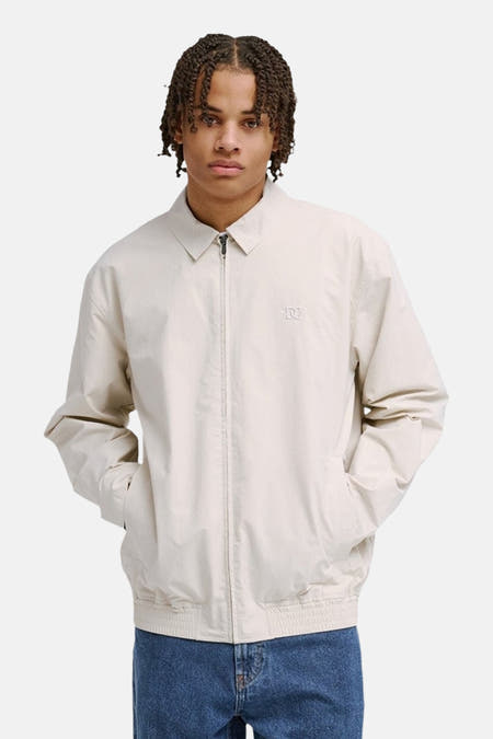 Beige korte jas van DC SHOES met rits en steekzakken, gedragen met een blauwe jeans.
