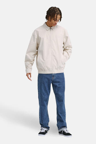 Manteau court beige de DC SHOES, avec manches longues, fermeture éclair et jean bleu.