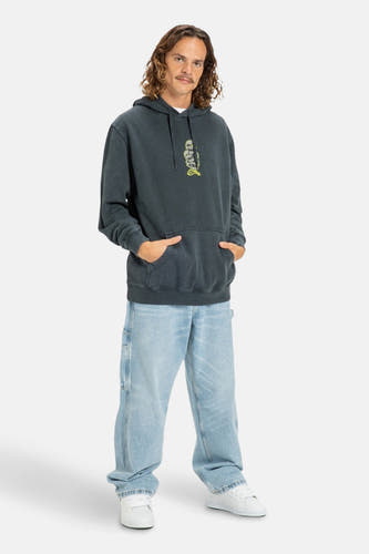 Pull-over gris avec capuche DC SHOES, imprimé d'un squelette sur la poitrine, associé à des jeans larges et des baskets blanches.