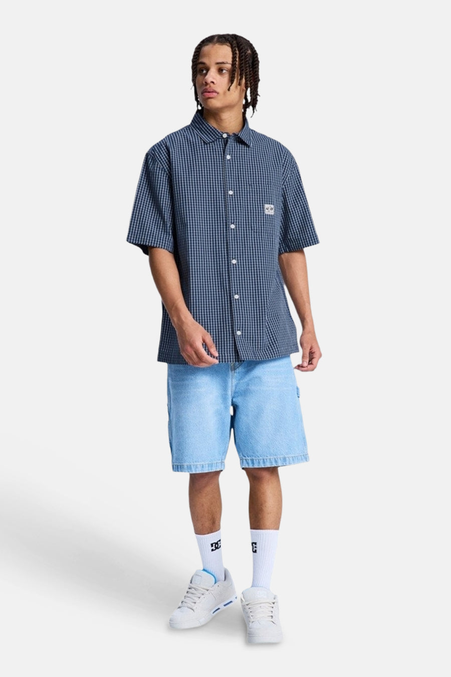 Blauw geruit hemd met korte mouwen van DC SHOES, gedragen door een man met denim shorts en sneakers.
