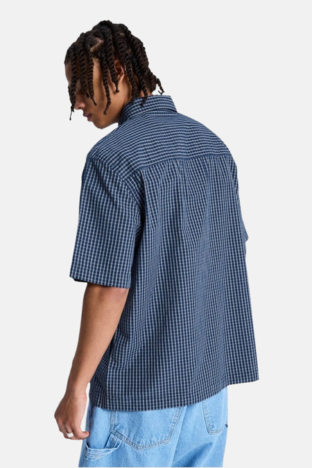 Blauw geruit hemd met korte mouwen van DC SHOES, aan de achterkant gedragen door een persoon met twists en lichtblauwe jeans.
