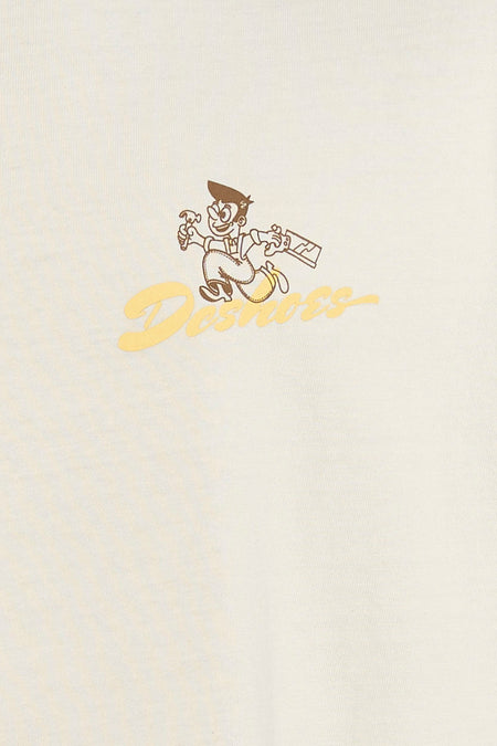 Beige T-shirt van DC SHOES, met een cartoonafbeelding en logo in gele en bruine tinten.