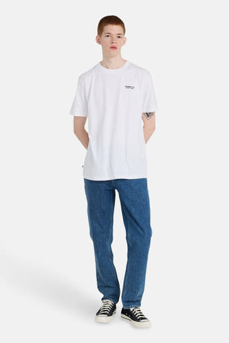 Blauwe straight jeans van ELEMENT, gecombineerd met een wit t-shirt en zwarte sneakers.