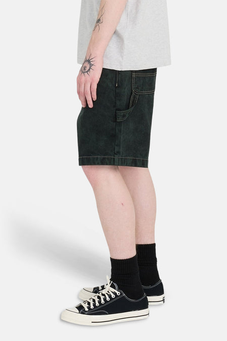 Groene jeansshort van ELEMENT, met steekzak, gedragen met zwarte sokken en lage zwarte schoenen, zijaanzicht.